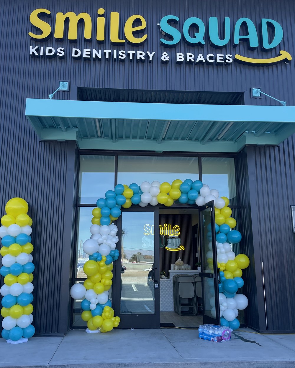 Balloon columns in blue, yellow and white flanking the doors of a kids dentistry storefront